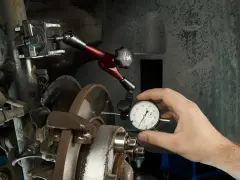 Mechanik mierzy bicie przy hamowaniu tarczy hamulcowej za pomocą czujnika zegarowego.