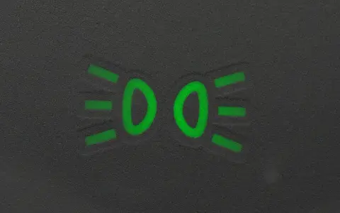 Zielony symbol świateł mijania na ciemnym tle.
